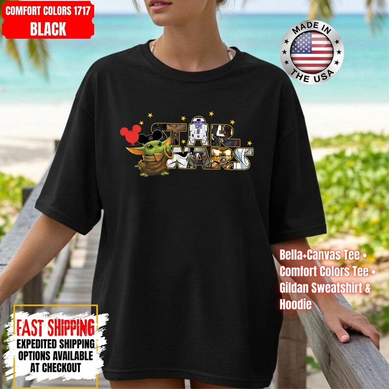 May include: Black t-shirt featuring a Star Wars graphic with Baby Yoda, Mickey Mouse ears, and other characters. The shirt includes the text "STAR WARS" and is made of Comfort Colors material. The shirt also has the text "MADE IN THE USA".