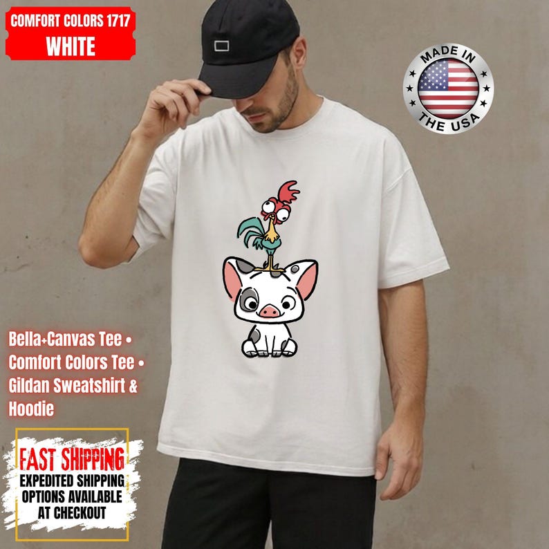 K&ouml;nnte beinhalten: Wei&szlig;es T-Shirt mit einer Cartoon-Illustration eines Schweins und eines Hahns. Das Shirt tr&auml;gt den Text "COMFORT COLORS 1717 WHITE" und "MADE IN THE USA". Das Shirt ist ein Bella-Canvas Tee, Comfort Colors Tee oder Gildan Sweatshirt & Hoodie.