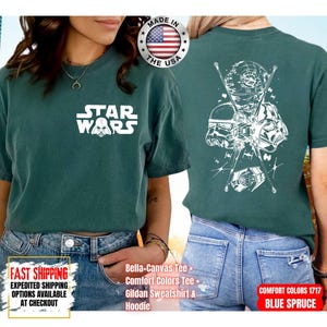 Op de afbeelding: Een tealkleurig T-shirt met het witte "Star Wars" logo op de voorkant. De achterkant toont een witte afbeelding van Star Wars-personages en -voertuigen. Gemaakt in de VS. Comfort Colors Tee.