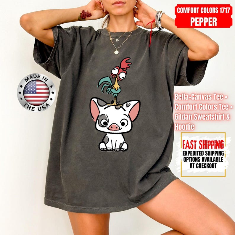 K&ouml;nnte beinhalten: Dunkelgraues Comfort Colors T-Shirt mit einem Cartoon-Schwein und Hahn-Design. Das Shirt enth&auml;lt den Text "MADE IN THE USA" und "COMFORT COLORS 1717 PEPPER". Es ist ein Bella-Canvas Tee, Comfort Colors Tee oder Gildan Sweatshirt & Hoodie.