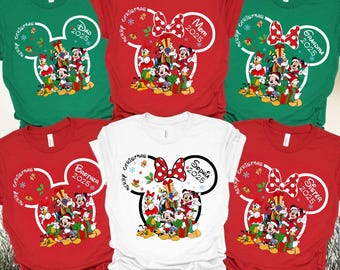 May include: A collection of Christmas-themed t-shirts in red, green, and white. Each shirt features a Minnie Mouse head design with a bow and a group of Disney characters. Text includes "Dad 2025", "Mom 2025", "Grandma 2025", "Brother 2025", "Sister 2025", and "Sophia 2025".