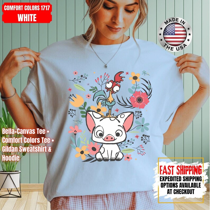May include: White tee shirt with a cartoon pig and rooster design, surrounded by flowers. The shirt includes the text "COMFORT COLORS 1717 WHITE". Made in the USA. The tee is a Bella+Canvas, Comfort Colors, or Gildan.