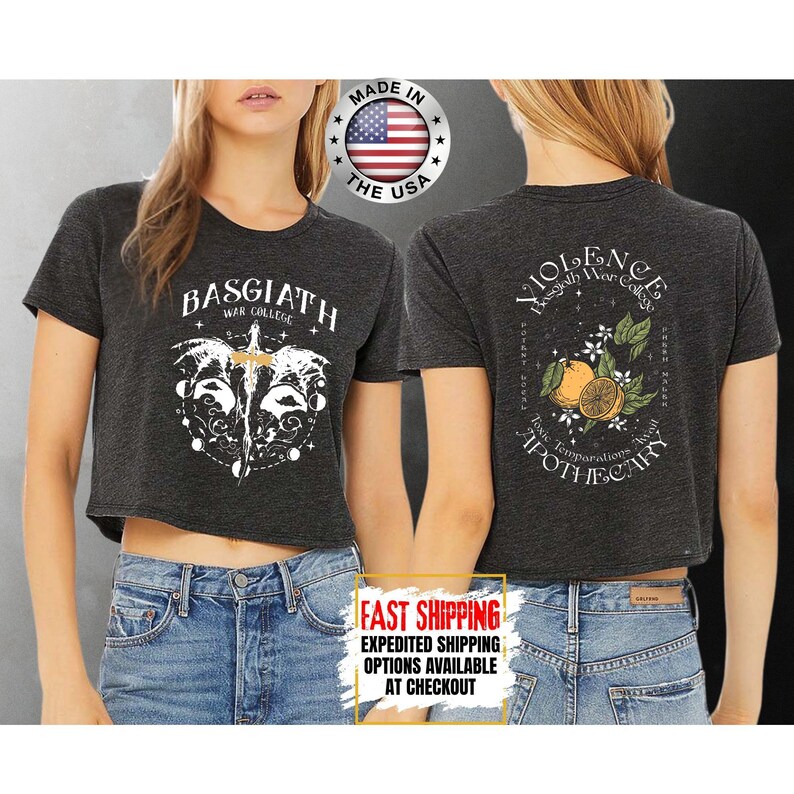 Puede incluir: Camisetas cortas de color gris oscuro con dise&ntilde;os gr&aacute;ficos y texto en blanco. Una camiseta presenta "BASGIATH WAR COLLEGE" y un dise&ntilde;o de espada. La otra camiseta tiene "VIOLENCE Basgiath War College" con un dise&ntilde;o naranja y floral. "MADE IN THE USA" est&aacute; impreso en la camiseta.
