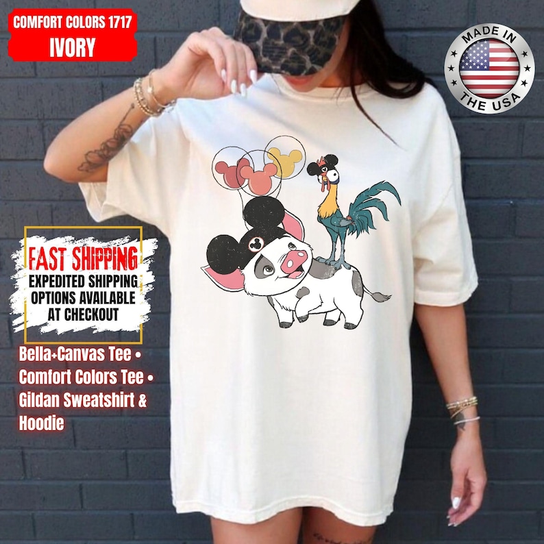 May include: Ivory Comfort Colors tee featuring a cartoon pig with Mickey Mouse ears, a rooster, and Mickey Mouse balloon graphics. The shirt has the text "FAST SHIPPING" and "MADE IN THE USA" on it. Bella-Canvas, Comfort Colors, and Gildan options are available.