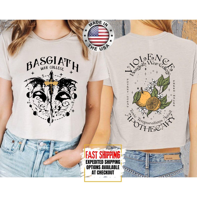 Puede incluir: Un crop top beige claro con el texto "BASGIATH WAR COLLEGE" y un gr&aacute;fico de espada y alas. La parte trasera de la camiseta presenta el texto "VIOLENCE Basgiath War College" con una ilustraci&oacute;n de c&iacute;tricos. Hecho en los EE. UU.