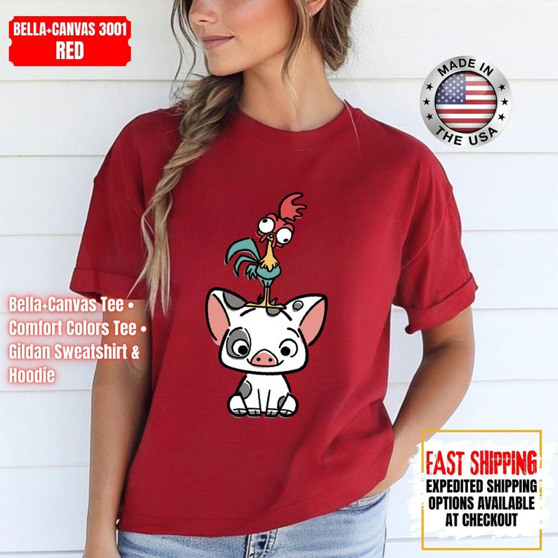 K&ouml;nnte beinhalten: Rotes T-Shirt mit einem Cartoon-Schwein und Hahn-Design. Das T-Shirt hat hochgekrempelte &Auml;rmel. Der Text "Bella-Canvas Tee, Comfort Colors Tee, Gildan Sweatshirt & Hoodie" steht links. Hergestellt in den USA.