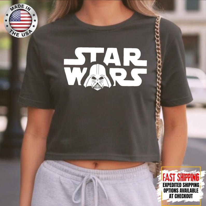 Puede incluir: Top corto gris oscuro con el logo blanco de 'Star Wars' y el casco de Darth Vader. Fabricado en EE. UU.