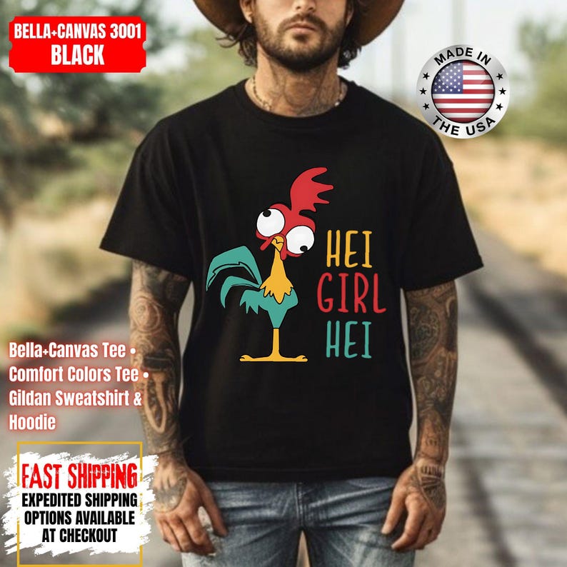 May include: Black t-shirt with a cartoon rooster design in red, teal, and yellow, and the words "HEI GIRL HEI". The top of the shirt has the text "BELLA-CANVAS 3001 BLACK".