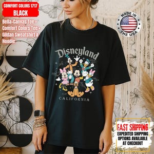 May include: Black Comfort Colors 1717 t-shirt featuring a Disneyland graphic with Mickey Mouse, Minnie Mouse, Goofy, Donald Duck, Daisy Duck, and Pluto. The shirt includes the text "Disneyland California".