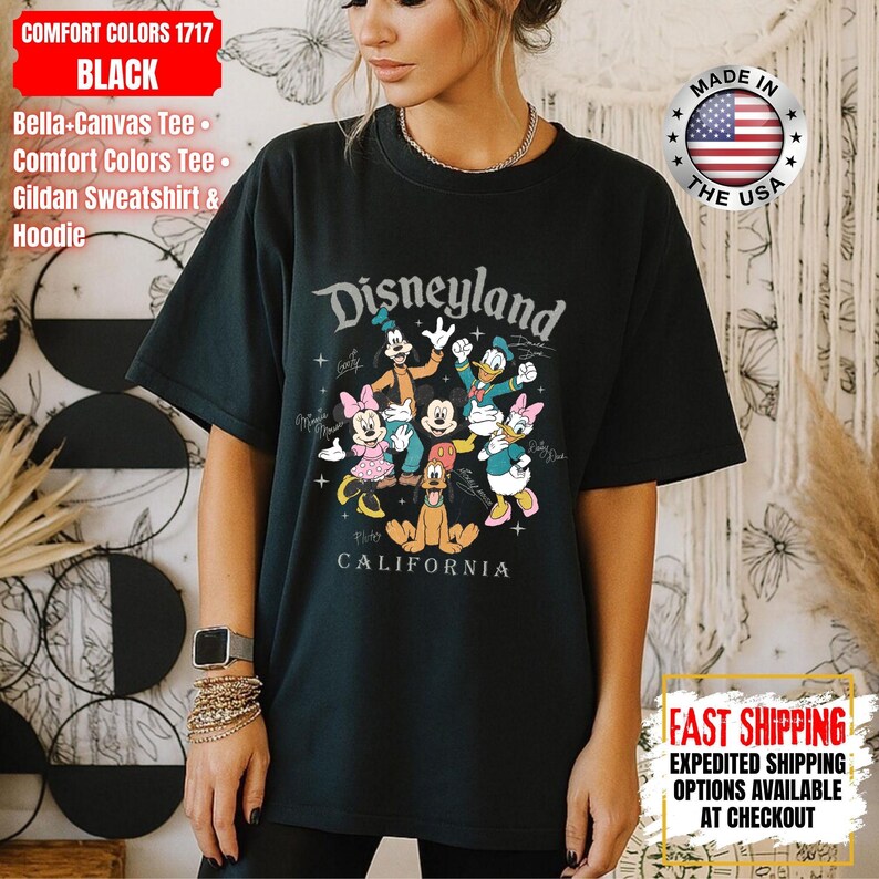 May include: Black Comfort Colors 1717 t-shirt featuring a Disneyland graphic with Mickey Mouse, Minnie Mouse, Goofy, Donald Duck, Daisy Duck, and Pluto. The shirt includes the text "Disneyland California".