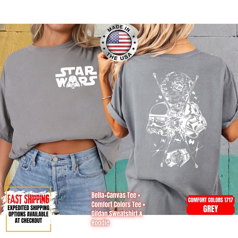 Op de afbeelding: Een grijs Comfort Colors T-shirt met het Star Wars-logo op de voorkant en een witte afbeelding van Star Wars-personages op de achterkant. Gemaakt in de VS.