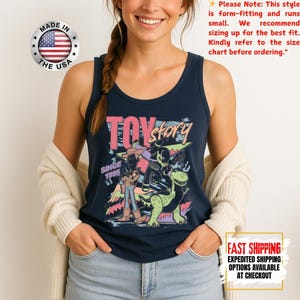 Op de afbeelding: Marineblauwe tanktop met een kleurrijke afbeelding van Toy Story-personages en de tekst "TOY STORY SINCE 1995." De tanktop heeft een ronde hals en is gemaakt in de VS.