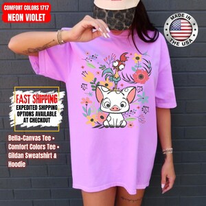 May include: Neon violet t-shirt with a cartoon pig and rooster design, encircled by flowers. The shirt displays the text "COMFORT COLORS 1717 NEON VIOLET". Made in the USA.