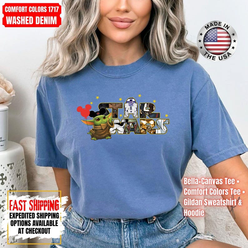 May include: A blue Comfort Colors t-shirt featuring the Star Wars logo with Baby Yoda holding Mickey Mouse balloons. The shirt also has the text "Made in the USA" and "Bella-Canvas Tee, Comfort Colors Tee, Gildan Sweatshirt & Hoodie."