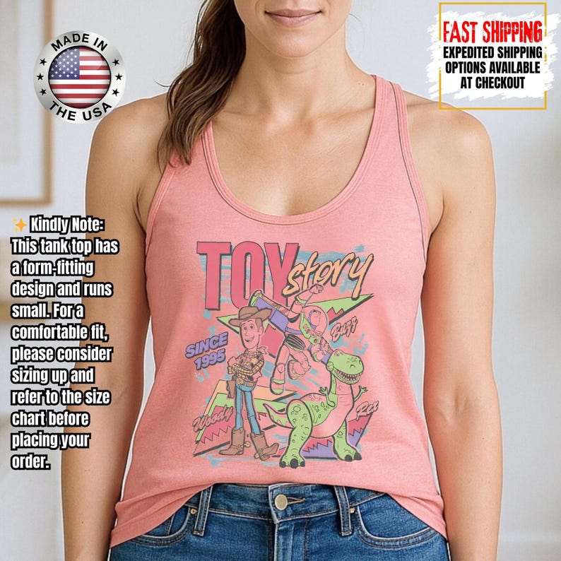 Op de afbeelding: Een lichtroze tanktop met een afbeelding van personages uit de film "Toy Story". Het ontwerp bevat Woody, Buzz Lightyear en Rex, met de woorden "Toy Story" en "Since 1995". De tanktop heeft een racerback-stijl.
