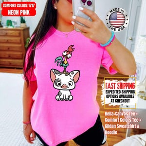 K&ouml;nnte beinhalten: Neonpinkfarbenes T-Shirt mit einer Cartoon-Illustration eines Schweins mit einem Hahn auf dem Kopf. Das Shirt tr&auml;gt den Text "COMFORT COLORS 1717 NEON PINK". Erh&auml;ltlich als Bella+Canvas Tee, Comfort Colors Tee oder Gildan Sweatshirt & Hoodie.