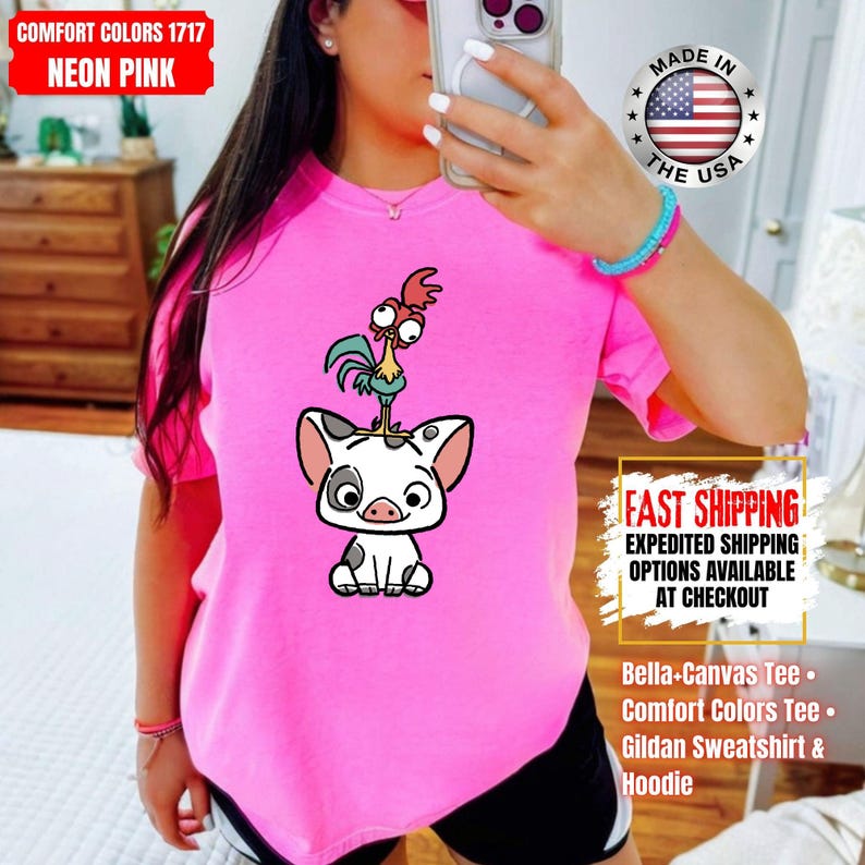 K&ouml;nnte beinhalten: Neonpinkfarbenes T-Shirt mit einer Cartoon-Illustration eines Schweins mit einem Hahn auf dem Kopf. Das Shirt tr&auml;gt den Text "COMFORT COLORS 1717 NEON PINK". Erh&auml;ltlich als Bella+Canvas Tee, Comfort Colors Tee oder Gildan Sweatshirt & Hoodie.