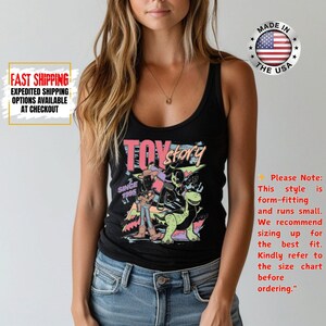 Op de afbeelding: Zwart tanktop met een kleurrijke afbeelding uit de film "Toy Story". De afbeelding bevat de tekst "Toy Story" en "Since 1995". De tanktop is nauwsluitend en valt klein.