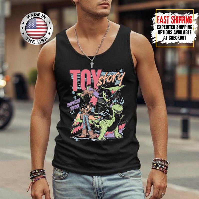 Op de afbeelding: Zwart tanktop met een kleurrijke "Toy Story" graphic. Het ontwerp bevat de tekst "Toy Story" en "Since 1995" met afbeeldingen van personages. Gemaakt in de VS.