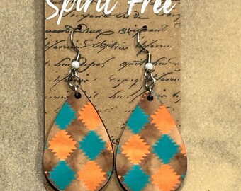 May include: Teal and orange geometric patterned teardrop shaped wooden earrings with silver hooks. The earrings are on a card that says "Spirit Free".