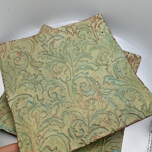 May include: Two square ceramic plates with a green and brown floral pattern. The plates are stacked on top of each other.