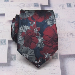 May include: A navy blue tie with a red and gray floral pattern. The tie has a silky texture and a classic design.