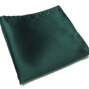 May include: A dark green satin pocket square. The square is folded and lying flat on a white surface.