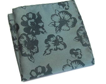 May include: A gray pocket square with a black floral pattern. The flowers are stylized and have a vintage look.