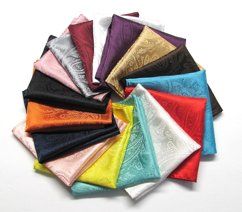 May include: A selection of folded paisley pocket squares in a range of colours, such as red, blue, yellow, and black. The pocket squares are arranged in a circular pattern, displaying their detailed designs and vibrant hues.