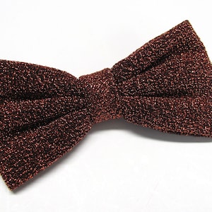 May include: A brown bow tie with a sparkly, textured fabric.