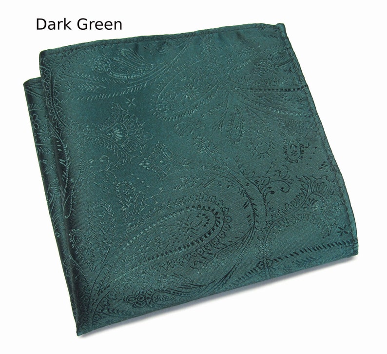 May include: A dark green paisley pocket square, folded neatly. The fabric has a subtle sheen, and the intricate pattern is visible across the surface. The text "Dark Green" is in the upper left corner.
