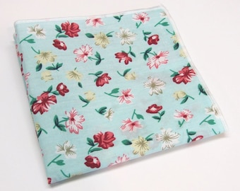May include: A light blue handkerchief with a floral pattern featuring red, white, and yellow flowers.