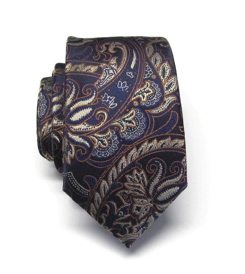 May include: A dark blue paisley patterned tie with brown and silver accents.