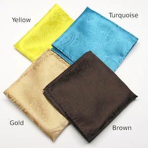 May include: Four silk pocket squares in yellow, turquoise, gold, and brown. Each square features a paisley pattern. The colours are vibrant and the fabric has a slight sheen. The pocket squares are neatly folded.