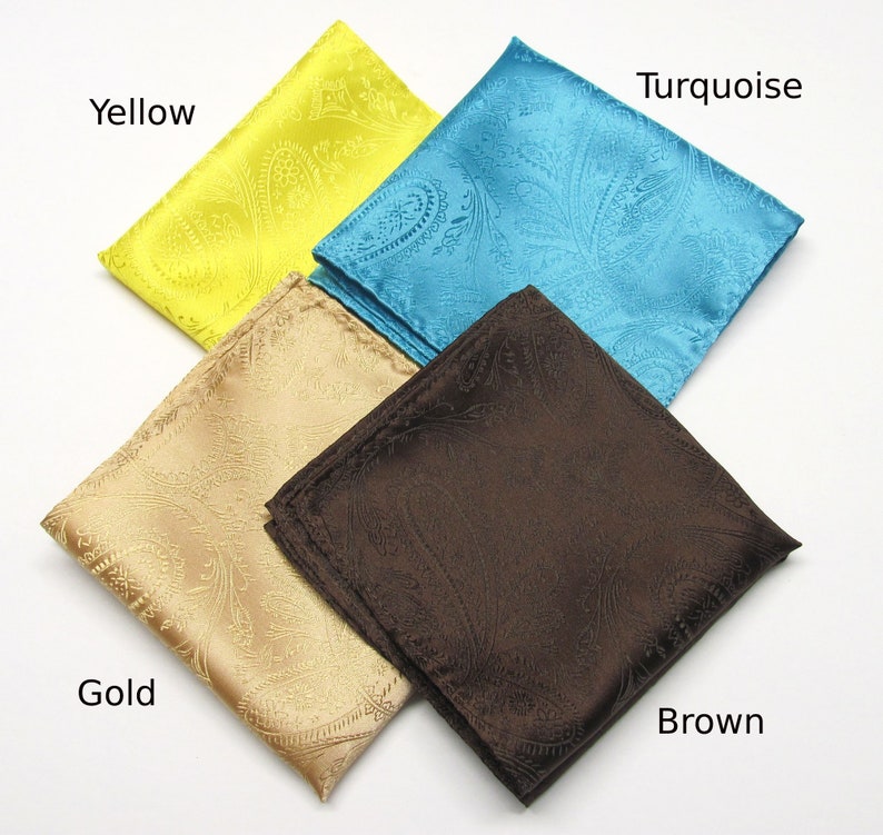 May include: Four silk pocket squares in yellow, turquoise, gold, and brown. Each square features a paisley pattern. The colours are vibrant and the fabric has a slight sheen. The pocket squares are neatly folded.