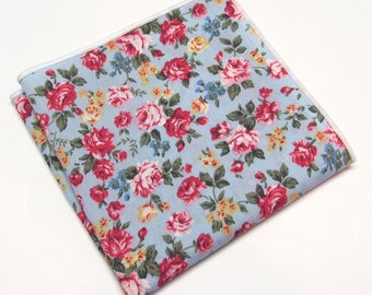 May include: A light blue pocket square with a floral pattern featuring pink, red, and yellow roses on a light blue background.