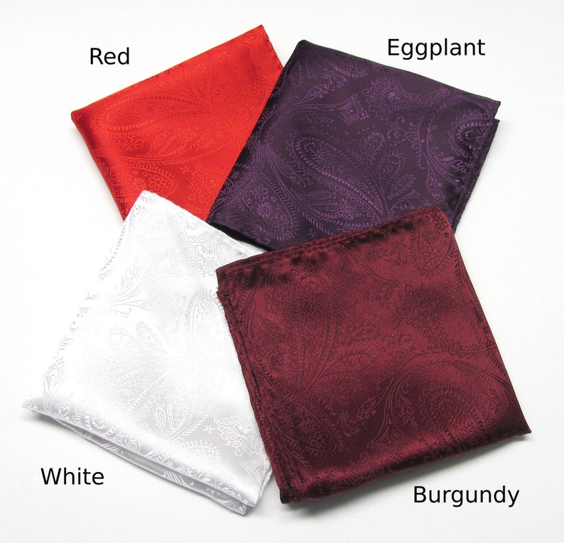 May include: Four paisley pocket squares in red, aubergine, white, and burgundy. Each square is folded and displayed with the colour name in the corner. The fabric has a subtle sheen.
