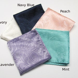 May include: A selection of folded paisley pocket squares in colours such as ivory, navy blue, peach, mint, and lavender. The fabric has a slight sheen, and the paisley pattern is visible.