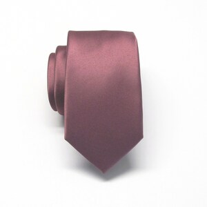 May include: A solid, deep pink satin necktie. The tie is folded in half and laid flat on a white surface.