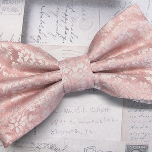 Puede incluir: Una pajarita rosa con un estampado floral blanco.