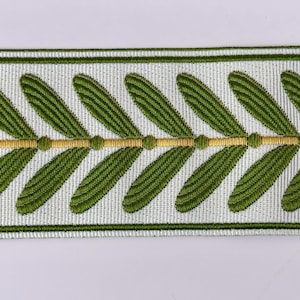 May include: Decorative trim featuring a repeating pattern of green leaves on a white background. A gold-colored line with small dots runs through the center of the design. The trim is bordered by thin green lines.