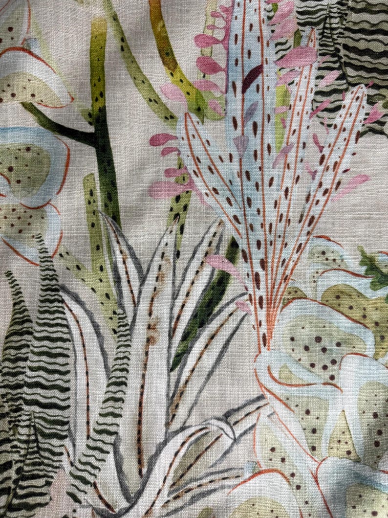 K&ouml;nnte beinhalten: Nahaufnahme eines Stoffes mit botanischem Druck, der verschiedene Kakteen und Sukkulenten zeigt. Das Design umfasst Wei&szlig;-, Gr&uuml;n-, Rosa- und Braunt&ouml;ne und erzeugt ein nat&uuml;rliches und strukturiertes Aussehen. Der Stoff hat eine leinenartige Textur.
