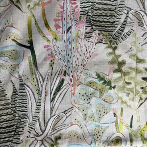 K&ouml;nnte beinhalten: Nahaufnahme eines Stoffes mit botanischem Druck. Das Design zeigt verschiedene Pflanzen in Gr&uuml;n-, Blau-, Rosa- und Beiget&ouml;nen. Der Stoff hat eine leinenartige Textur mit detaillierten und abstrakten Pflanzenillustrationen.