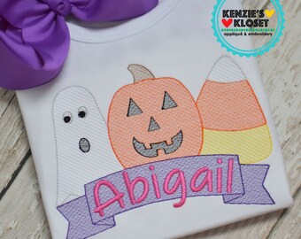 May include: White onesie with purple bow, embroidered with a ghost, pumpkin, and candy corn. The text "Abigail" is embroidered on a purple banner.