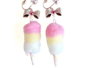 May include: A pair of clip-on earrings featuring pink, yellow, and white cotton candy with a silver bow and pink rhinestone.