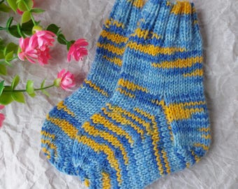 May include: A pair of hand-knitted socks featuring a variegated pattern of light blue, dark blue, and golden yellow yarn. The socks have a ribbed cuff at the top and a classic heel construction, showcasing a consistent knit texture throughout the design.