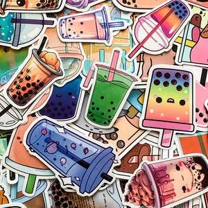 May include: A collection of colorful bubble tea stickers featuring various designs, including a green tea with boba, a blue space-themed cup, a pink and purple popsicle with a face, and a brown cup with a pink and white swirl design.