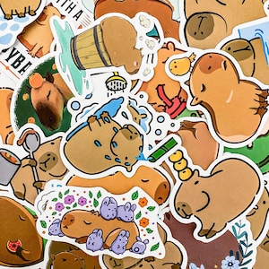 May include: A collection of colorful stickers featuring cartoon capybaras in various poses and activities, including taking a bath, playing in the water, and relaxing. The stickers are printed on white paper and have a glossy finish.