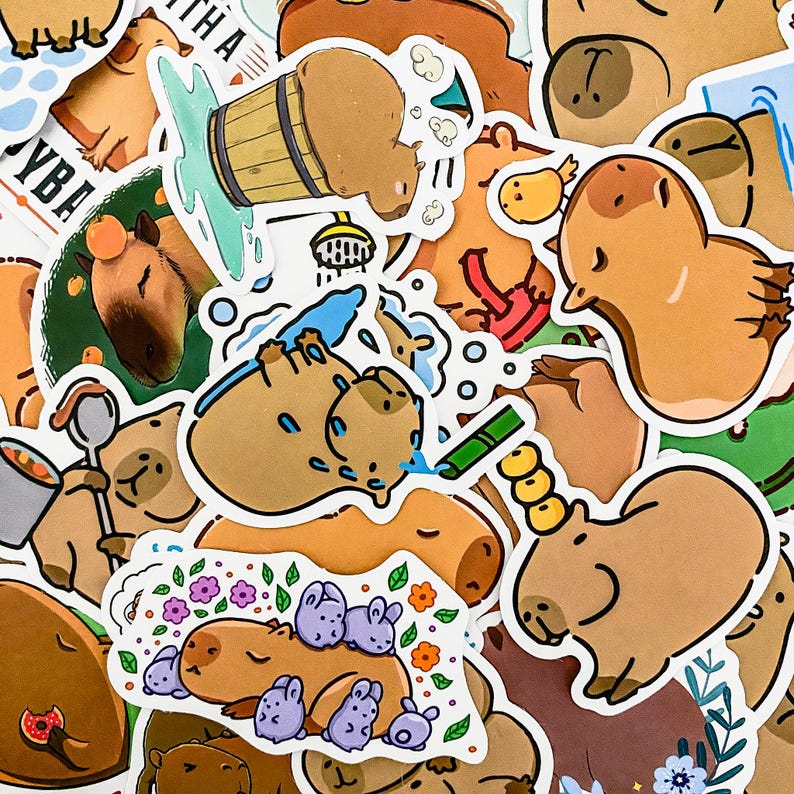 May include: A collection of colorful stickers featuring cartoon capybaras in various poses and activities, including taking a bath, playing in the water, and relaxing. The stickers are printed on white paper and have a glossy finish.