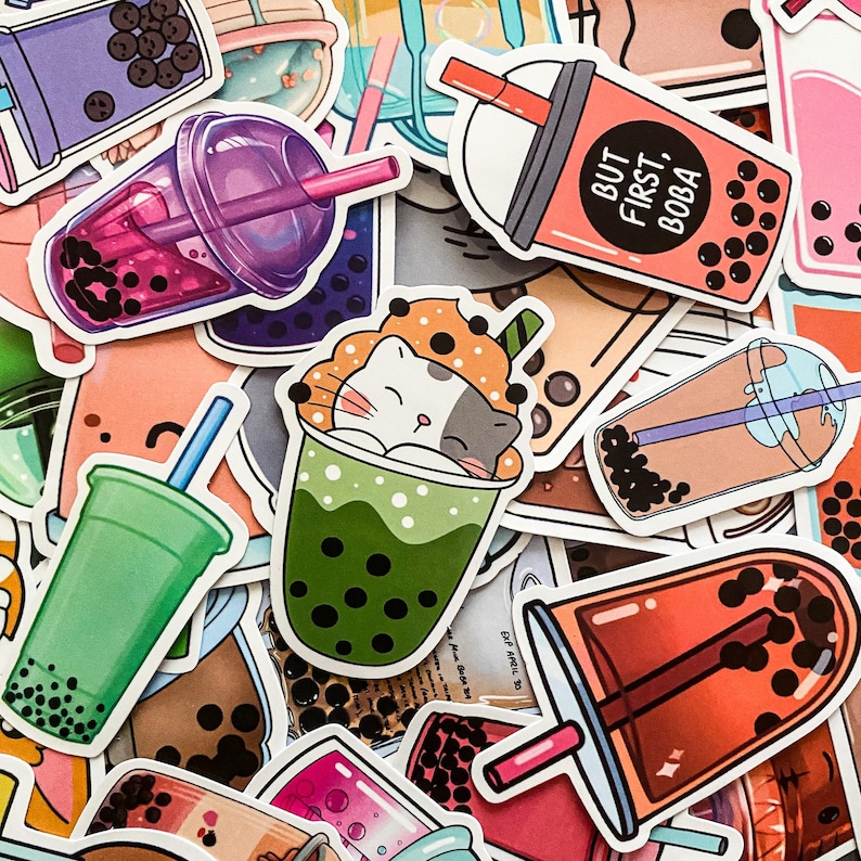 May include: A collection of colorful stickers featuring various bubble tea designs. The stickers include a cat sleeping in a cup of green tea, a cup of pink tea with boba, and a cup of orange tea with boba. The stickers also feature the text "But First, Boba".